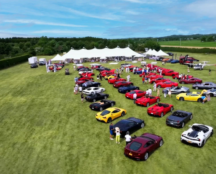 Rows of Ferraris drawn up on the lawn before the white luncheon marquee, seen from above, at The Concours Luncheon in Bridgehampton, New York, an early-June engagement in the season calendar of The Mansa Court