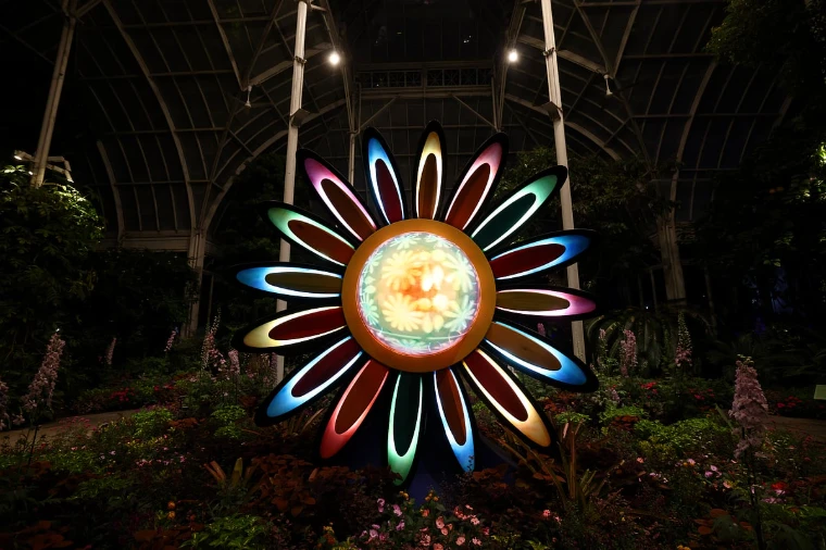 A lit sculpture of a flower among the beds inside the Conservatory on the night of the Ball (2026). The Conservatory Ball at the New York Botanical Garden, the Bronx, in the season calendar of The Mansa Court
