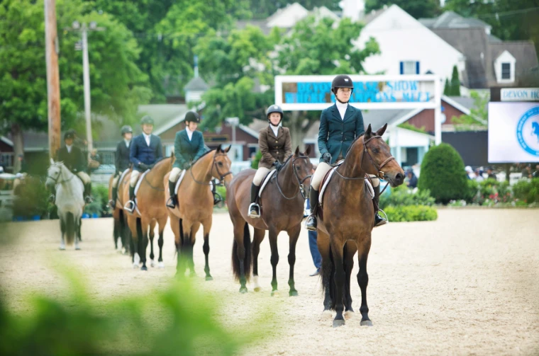 Riders in hunt coats wait with their horses in line for the judge. The Devon Horse Show and Country Fair at the Devon Show Grounds, Pennsylvania, in the season calendar of The Mansa Court