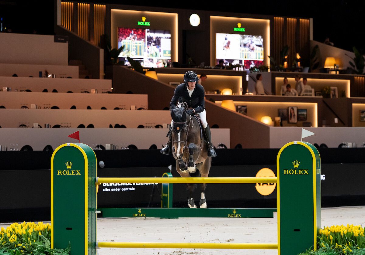 A horse and rider over a Rolex fence in front of the hospitality boxes at The Dutch Masters, the March indoor show kept in The Mansa Court calendar