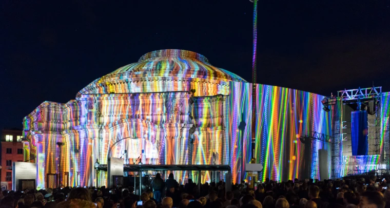 Rainbow light projections cover the domed facade of the Usher Hall at night as a large crowd watches from the street (2015). The Edinburgh International Festival, Usher Hall, Edinburgh, Scotland, in the season calendar of The Mansa Court