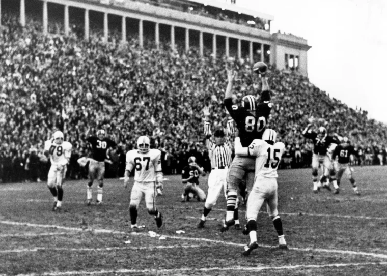 A black-and-white photograph of The Game before packed stands, players leaping for a pass. The Game, Harvard v Yale, An earlier Game, in the season calendar of The Mansa Court