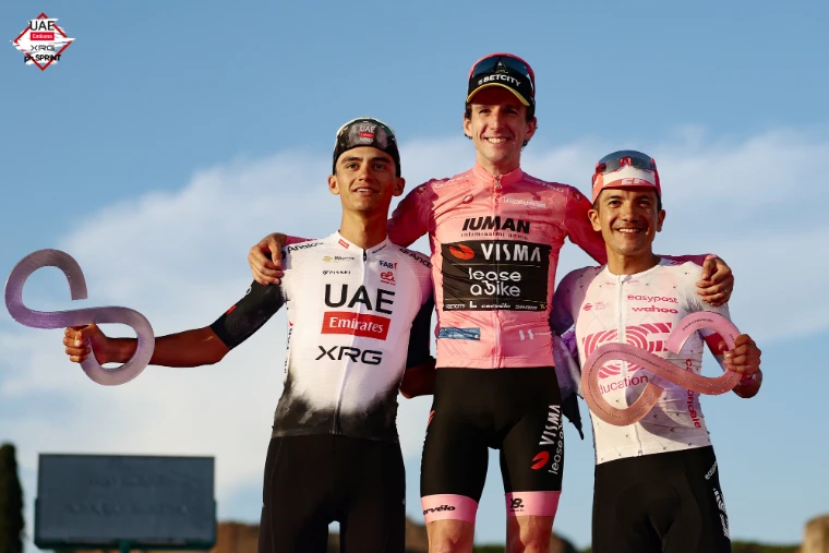 The final podium in Rome, the winner in the pink jersey between the second and third placed riders with their trophies, in 2025. The Giro d’Italia, in the season calendar of The Mansa Court