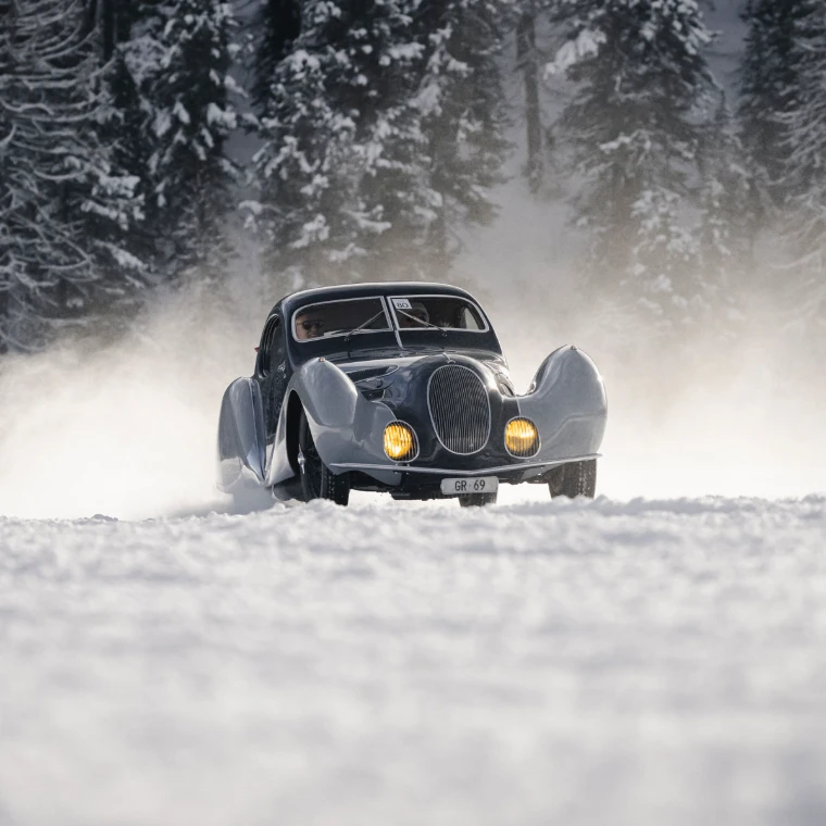 The 1937 Talbot-Lago T150C SS ‘Teardrop’, Best in Show in 2026, driven through a spray of snow before snow-covered pines. The I.C.E. St. Moritz, Lake St. Moritz, St. Moritz, Switzerland, in the season calendar of The Mansa Court