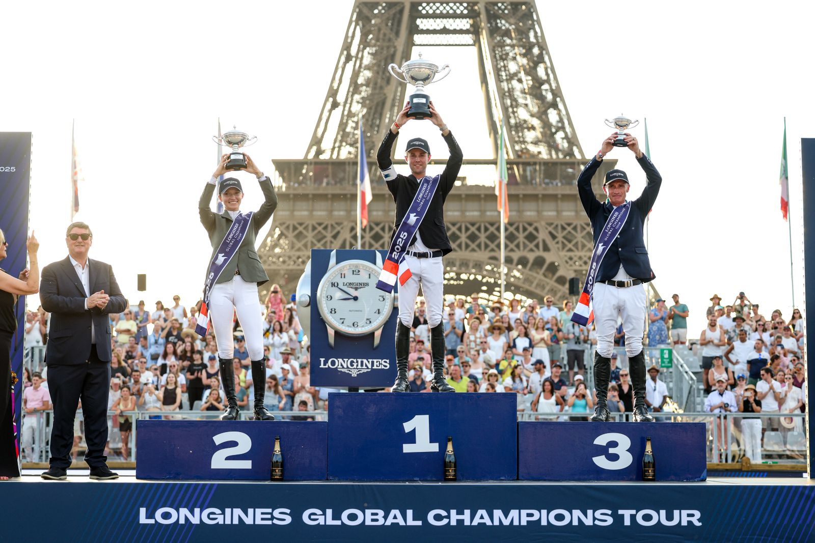 The three placed riders raising their trophies on the podium before the Eiffel Tower at the Longines Global Champions Tour Paris, a meeting The Mansa Court keeps in its calendar