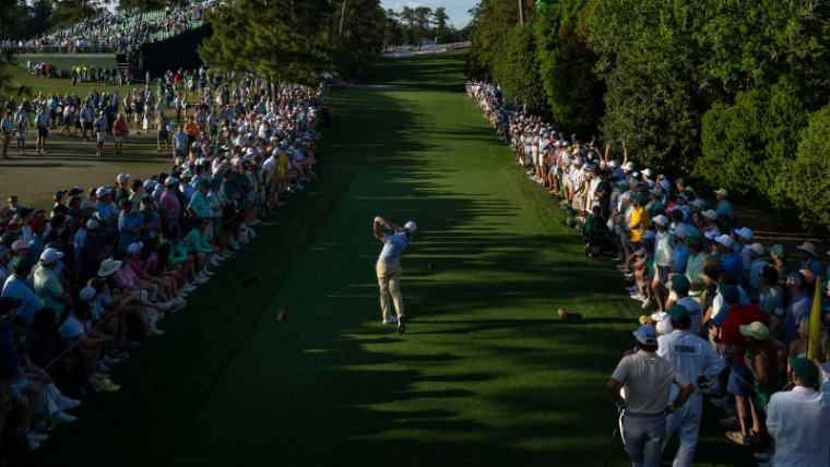A player driving down a pine-lined fairway between the galleries in late light at The Masters, Augusta National, where The Mansa Court seeks passage for members each April