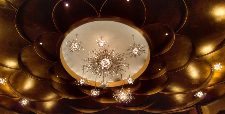 Starburst crystal chandeliers hang from the gold, petal-shaped ceiling of the Metropolitan Opera auditorium (2016).