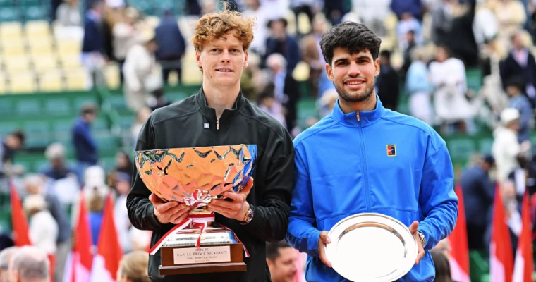 Jannik Sinner holding the champion’s trophy beside runner-up Carlos Alcaraz at the 2026 Rolex Monte-Carlo Masters presentation, an April engagement in the season calendar of The Mansa Court