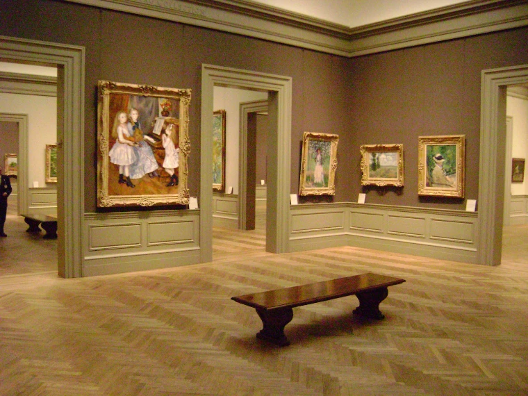 An empty gallery of nineteenth-century paintings in gilt frames, with a wooden bench on a herringbone parquet floor (2008).
