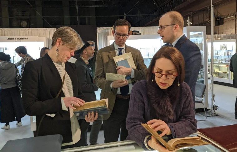 Collectors examine leather-bound volumes at a dealer’s stand (2025). The New York International Antiquarian Book Fair, Park Avenue Armory, New York, in the season calendar of The Mansa Court