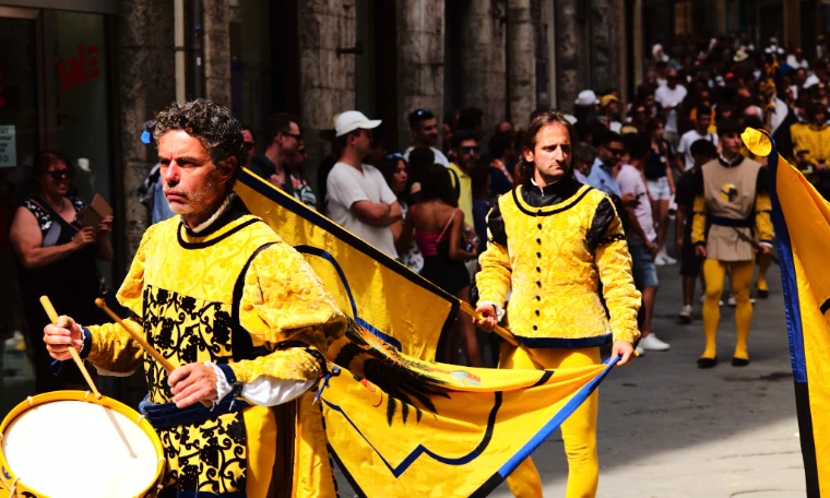 A drummer and an ensign of the Contrada dell’Aquila, in yellow, black and blue, in the streets of Siena (August 2024).