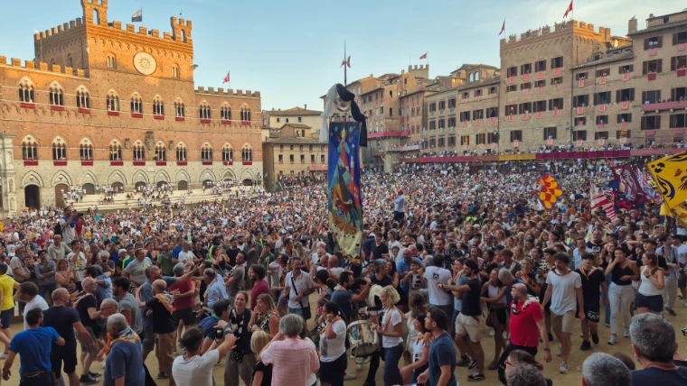 The painted banner, the Palio itself, carried high through the crowd in the Campo after the race (August 2024).