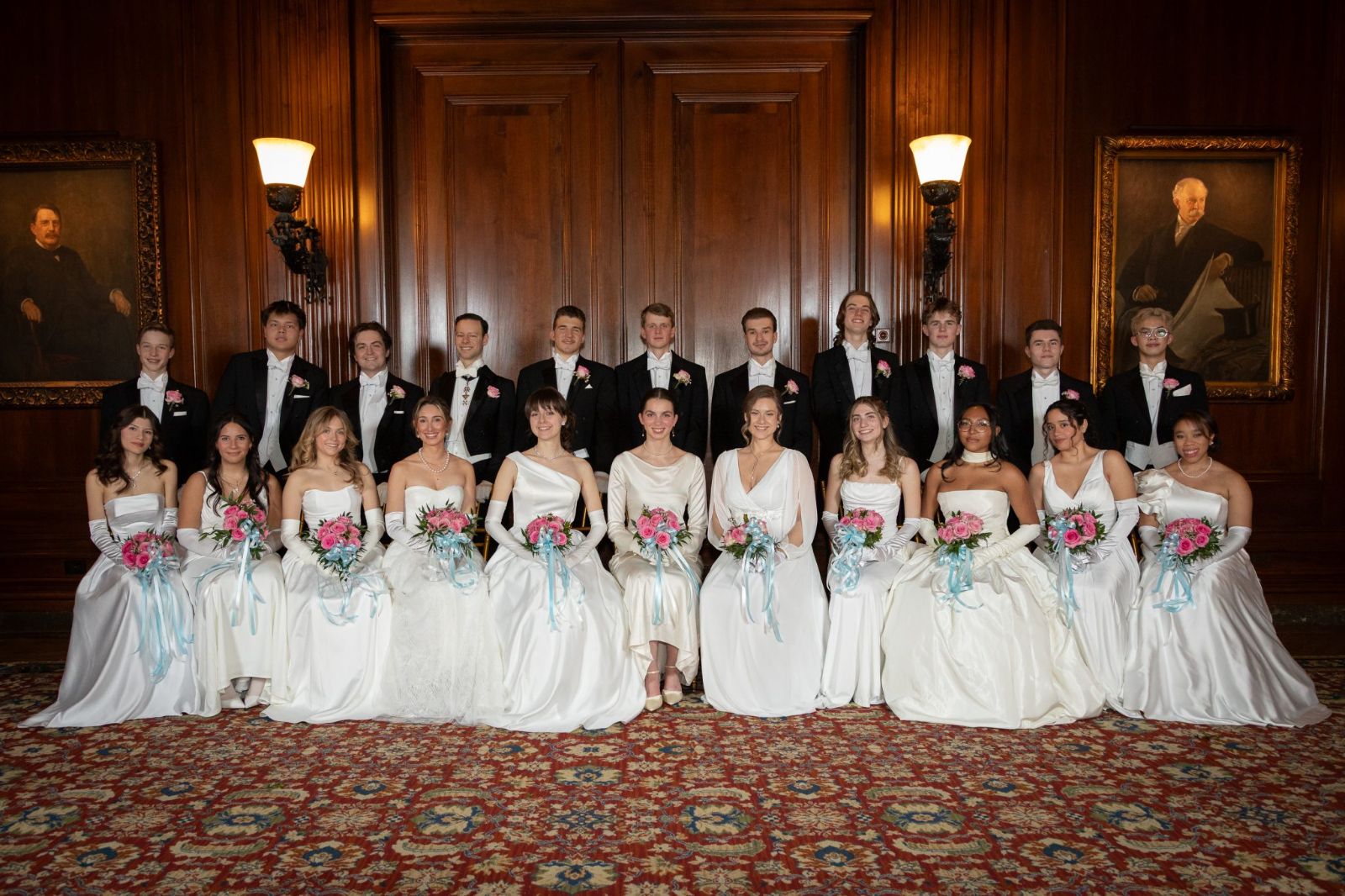 The debutantes in white gowns and their escorts in white tie, seated for the portrait at the Piarist Debutante Ball