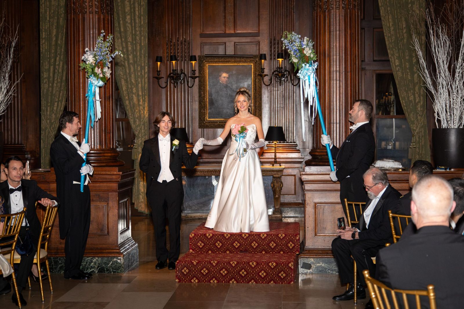 A debutante presented between the standards at the Piarist Debutante Ball