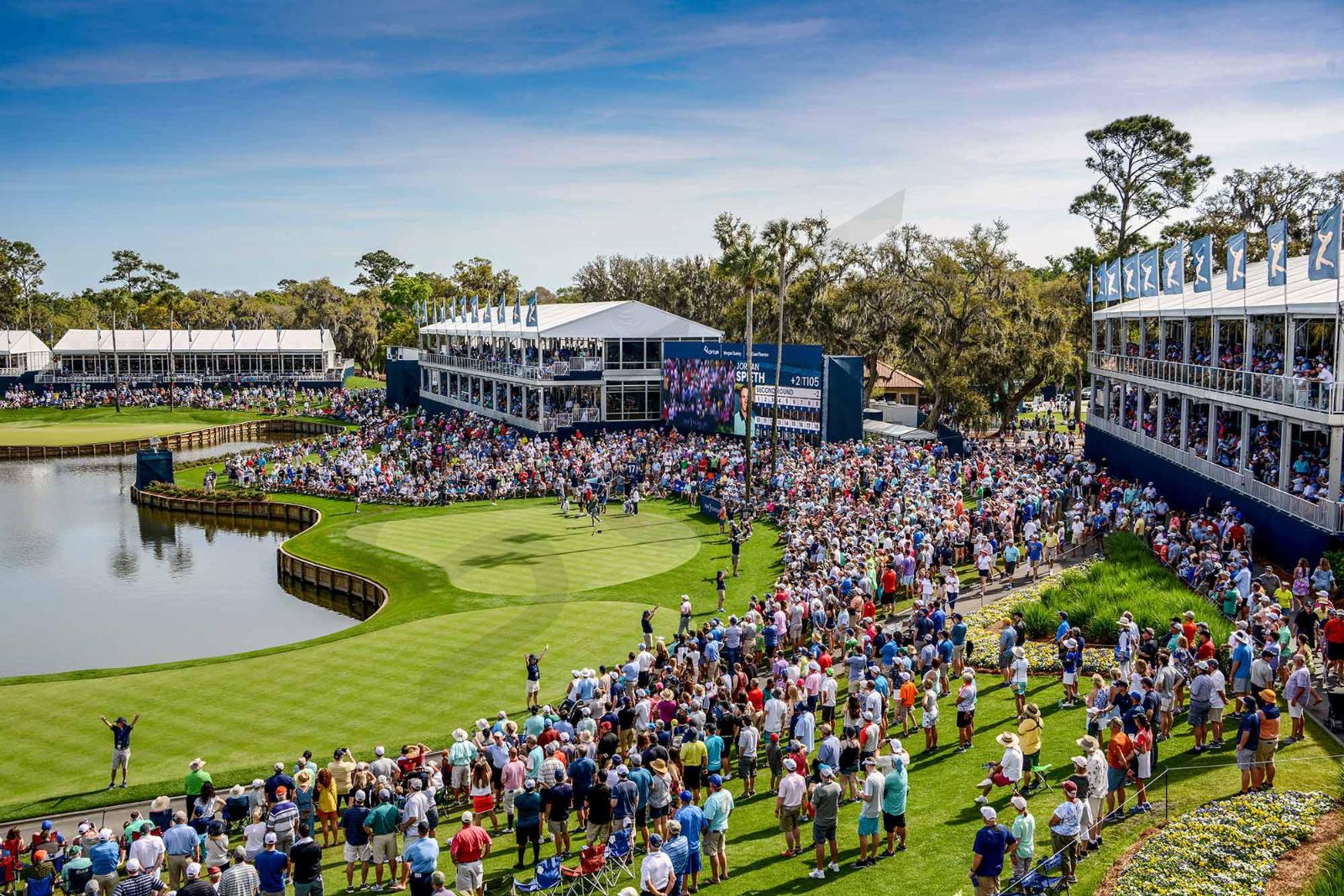 The island green seventeenth ringed by grandstands and hospitality pavilions at The Players Championship, TPC Sawgrass, attended by members of The Mansa Court