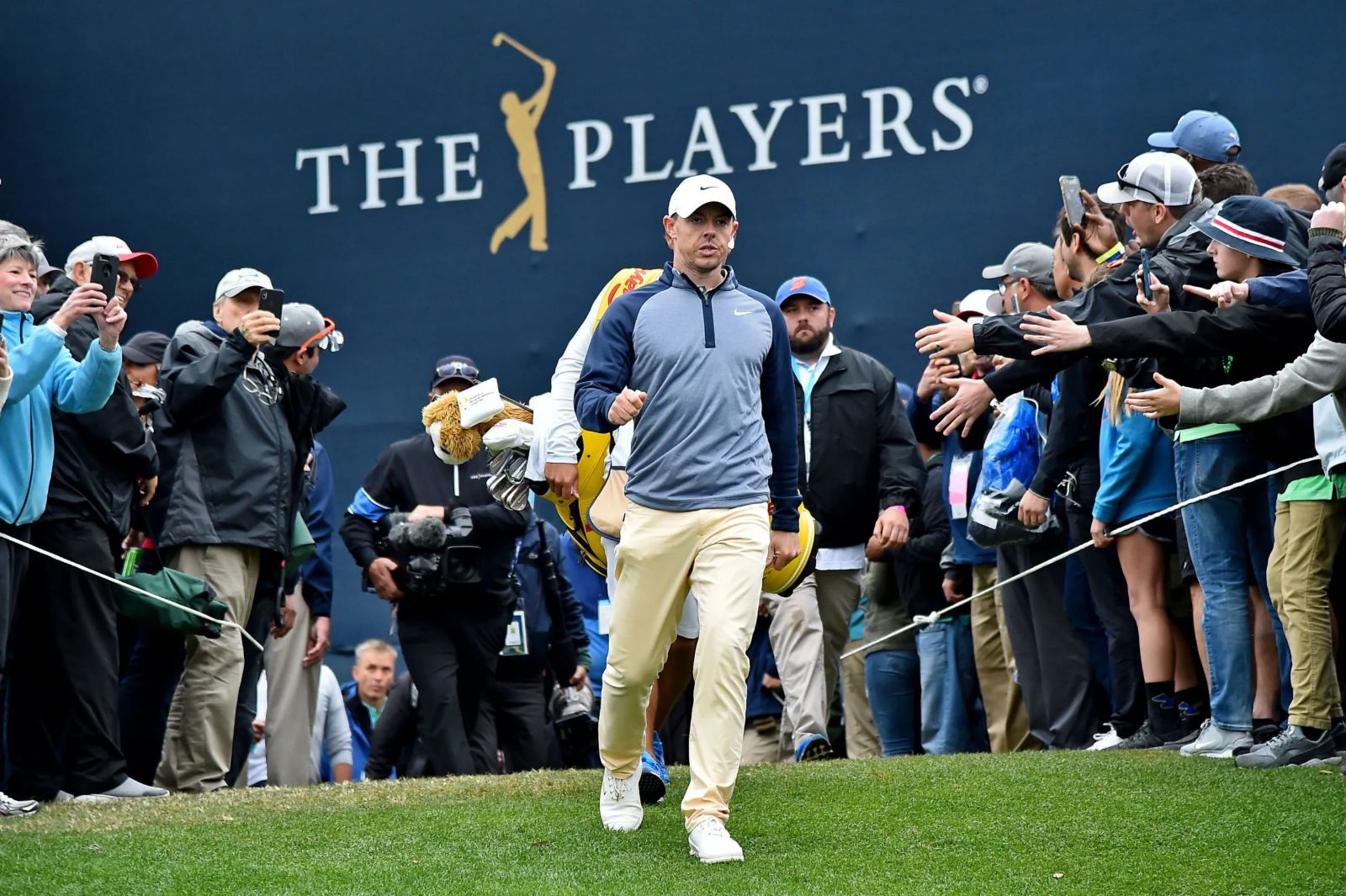 A player walking to the tee past the gallery and the tournament wall at The Players Championship, TPC Sawgrass, in The Mansa Court season calendar