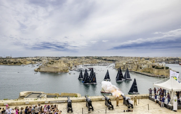 Smoke from the start gun drifts over the Saluting Battery as the fleet sets off across Grand Harbour, watched by crowds along the bastion (2025).