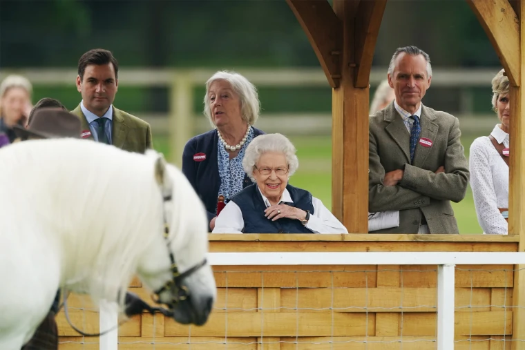 Spectators smile from a wooden stand as a white pony is shown in the ring, in 2022. The Royal Windsor Horse Show in the Home Park, Windsor, in the season calendar of The Mansa Court