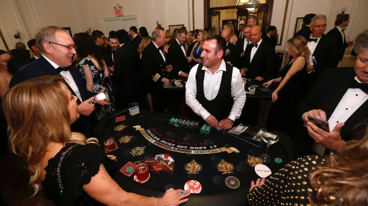 A dealer at the blackjack table among guests in black tie and an officer in uniform at The Sailors Ball in New York, an April engagement in the season calendar of The Mansa Court