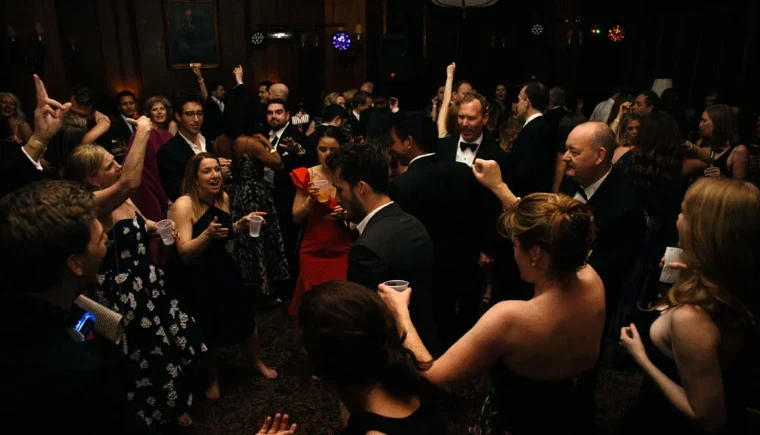 Guests in black tie and evening dresses dancing with their hands raised in a panelled room at The Sailors Ball in New York, an April engagement in the season calendar of The Mansa Court