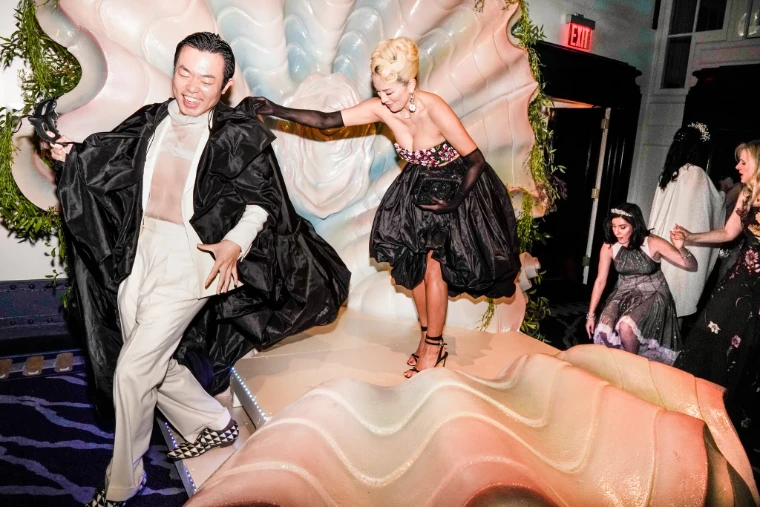 Guests in capes and ball gowns dancing on the stage before a giant scallop shell at The Save Venice Ball in New York, a late-April engagement in the season calendar of The Mansa Court