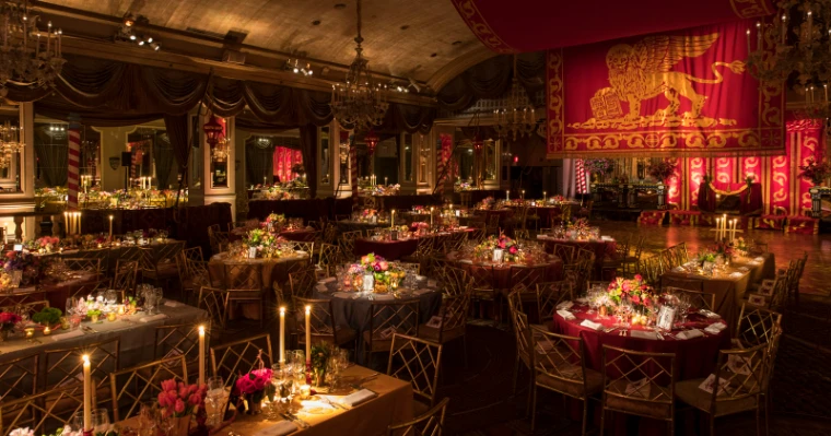 The ballroom set for dinner by candlelight beneath the banner of the Lion of Saint Mark at The Save Venice Ball in New York, a late-April engagement in the season calendar of The Mansa Court