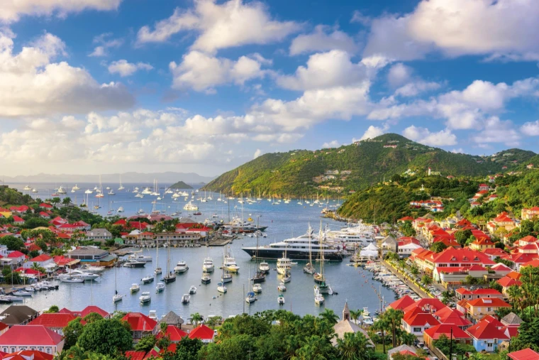 Red roofs and the harbour of Gustavia, superyachts at anchor beyond. Gustavia, St. Barthélemy, shown for The St. Barths Bucket in the season calendar of The Mansa Court