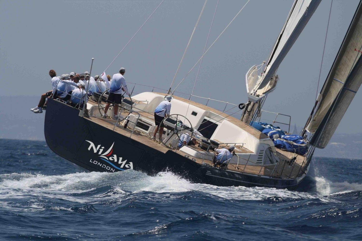 A superyacht heeling on the beat with her crew sitting out on the rail at The Superyacht Challenge, attended by members of The Mansa Court