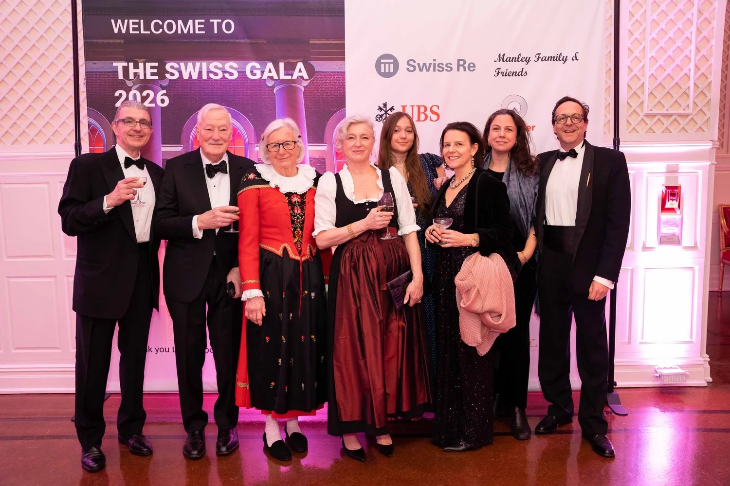 Guests in black tie and Swiss traditional dress raising a glass at the welcome to The Swiss Ball, New York, attended by members of The Mansa Court