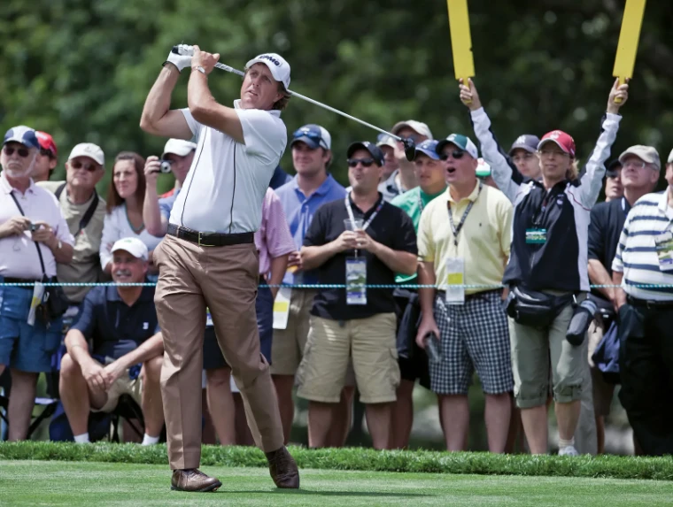 A player following his drive from the tee before a gallery of spectators and marshals raising quiet signs at the US Open, an engagement in the season calendar of The Mansa Court