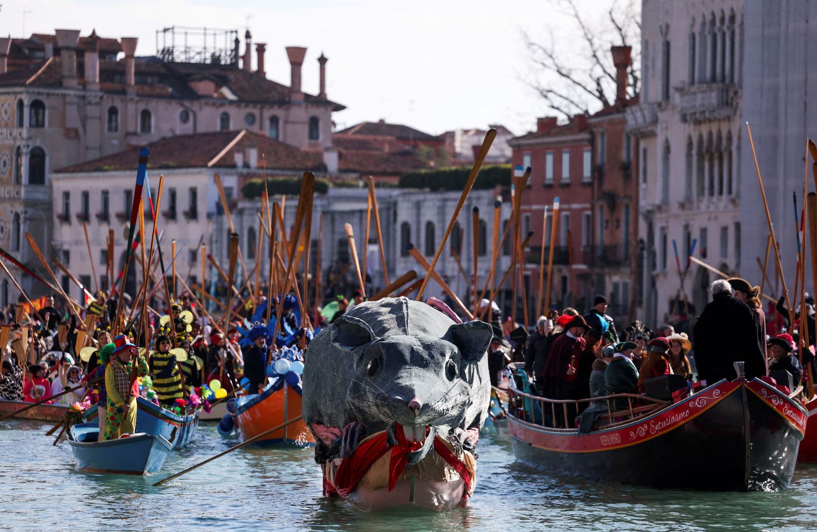 The great papier-mâché rat float leading the costumed rowing boats along the canal before the palazzi at The Venice Carnival