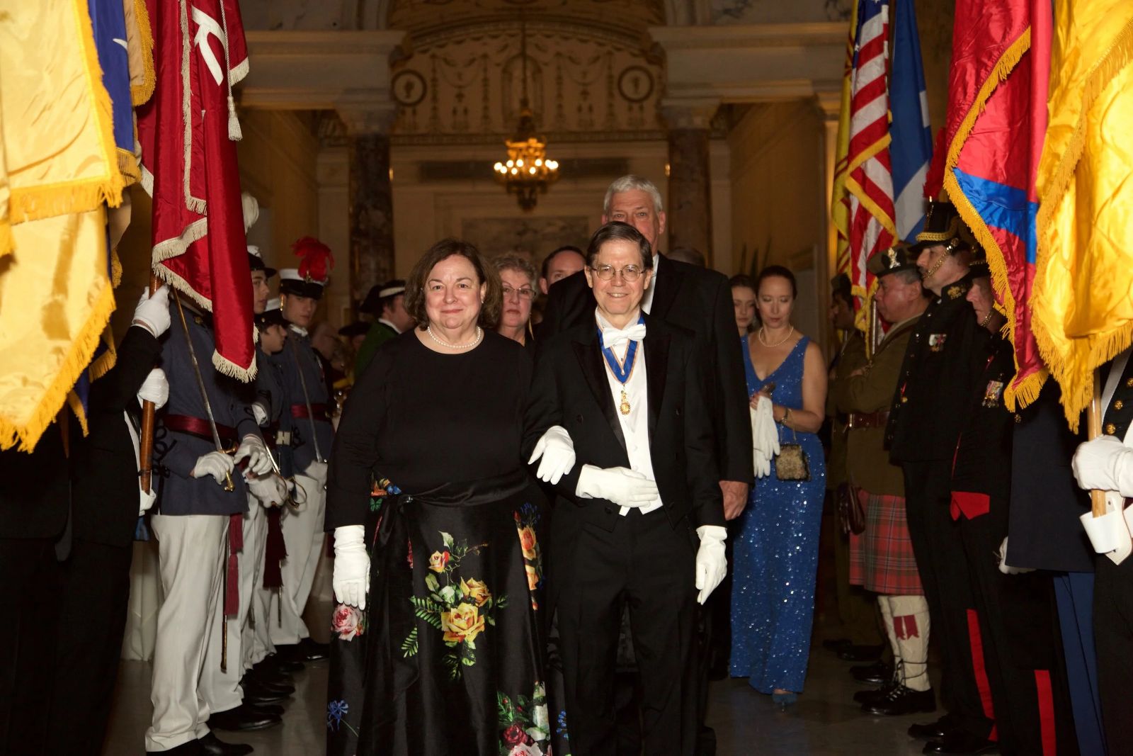 Guests in white tie processing between a colour guard of standards at The Washington Birthday Ball