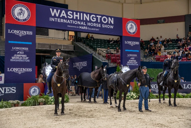 Black horses and uniformed soldiers of the Caisson Platoon in the arena beneath the show’s red, white and blue entrance arch (2022).
