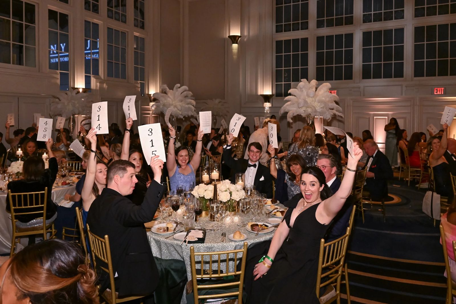 Guests in black tie raising numbered paddles during the appeal at The Winter Ball, New York