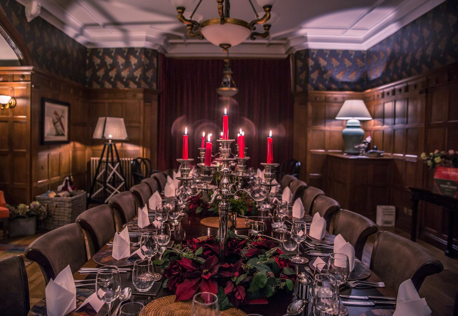 A long dinner table laid and lit by candlelight