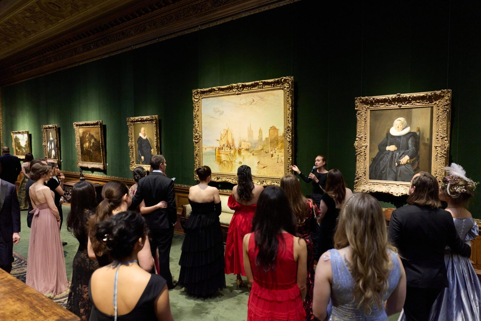Guests in gowns and black tie gathered for a curator’s talk before a Turner in the green West Gallery at The Young Fellows Ball, The Frick Collection, New York