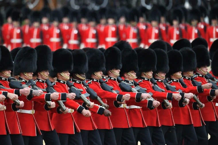 Guardsmen in bearskins and scarlet tunics march past in close order. Trooping the Colour on Horse Guards Parade, London, in the season calendar of The Mansa Court