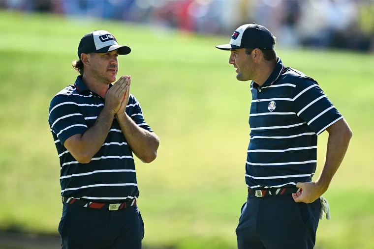 Two players in striped team shirts confer on the green as the gallery looks on. The PGA Championship, at US PGA Championship, in the season calendar of The Mansa Court