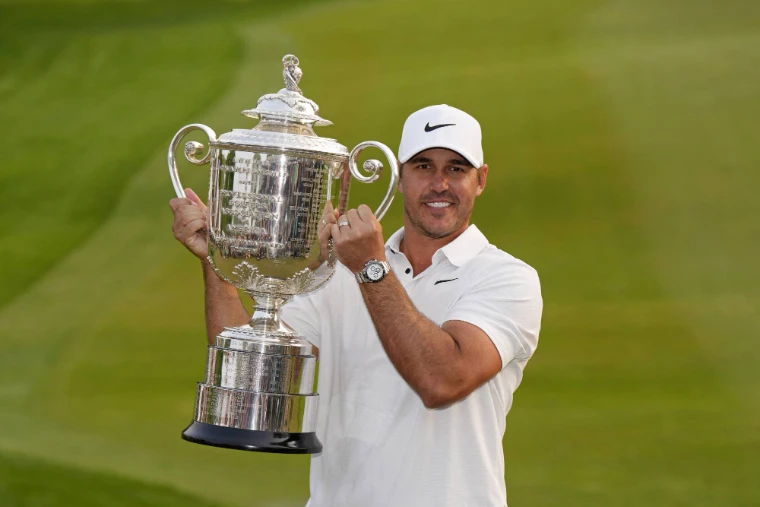A champion in white raises the Wanamaker Trophy against the green of the course, in 2023. The PGA Championship, at US PGA Championship, in the season calendar of The Mansa Court