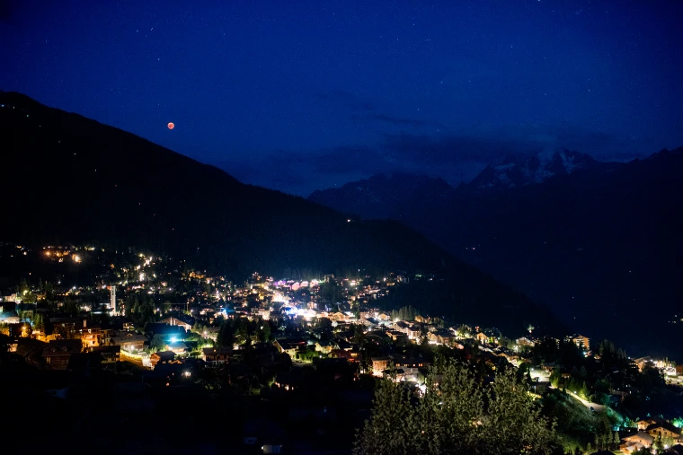 Verbier by night beneath a red moon, the village lit on the mountainside.