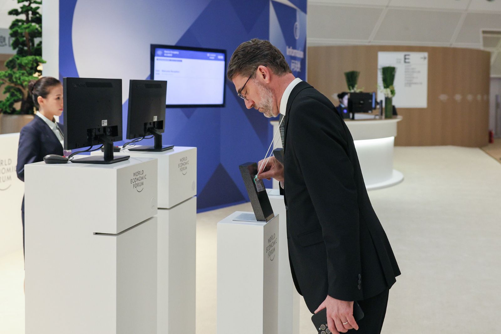 A participant collecting his badge at the registration desk at Davos